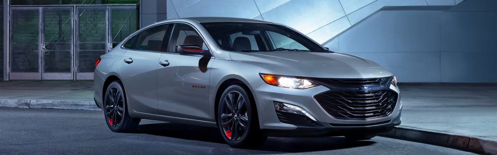 2025 Chevy Malibu parked by a sidewalk at night