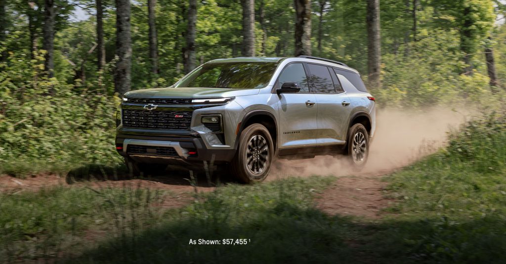 2026 Chevy Traverse driving on a forest trail with dust behind it.
