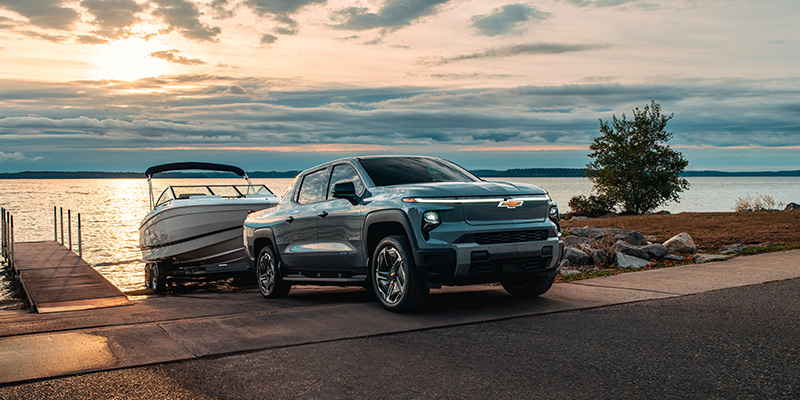 Chevrolet Silverado parked at sunset, showcasing its sleek design against a vibrant orange and purple sky.